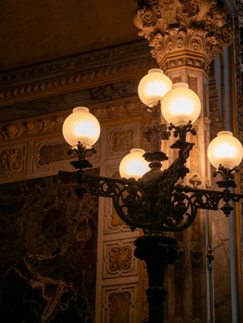 Free A classic vintage lamp casting warm light in an ornate, richly decorated interior space. Stock Photo