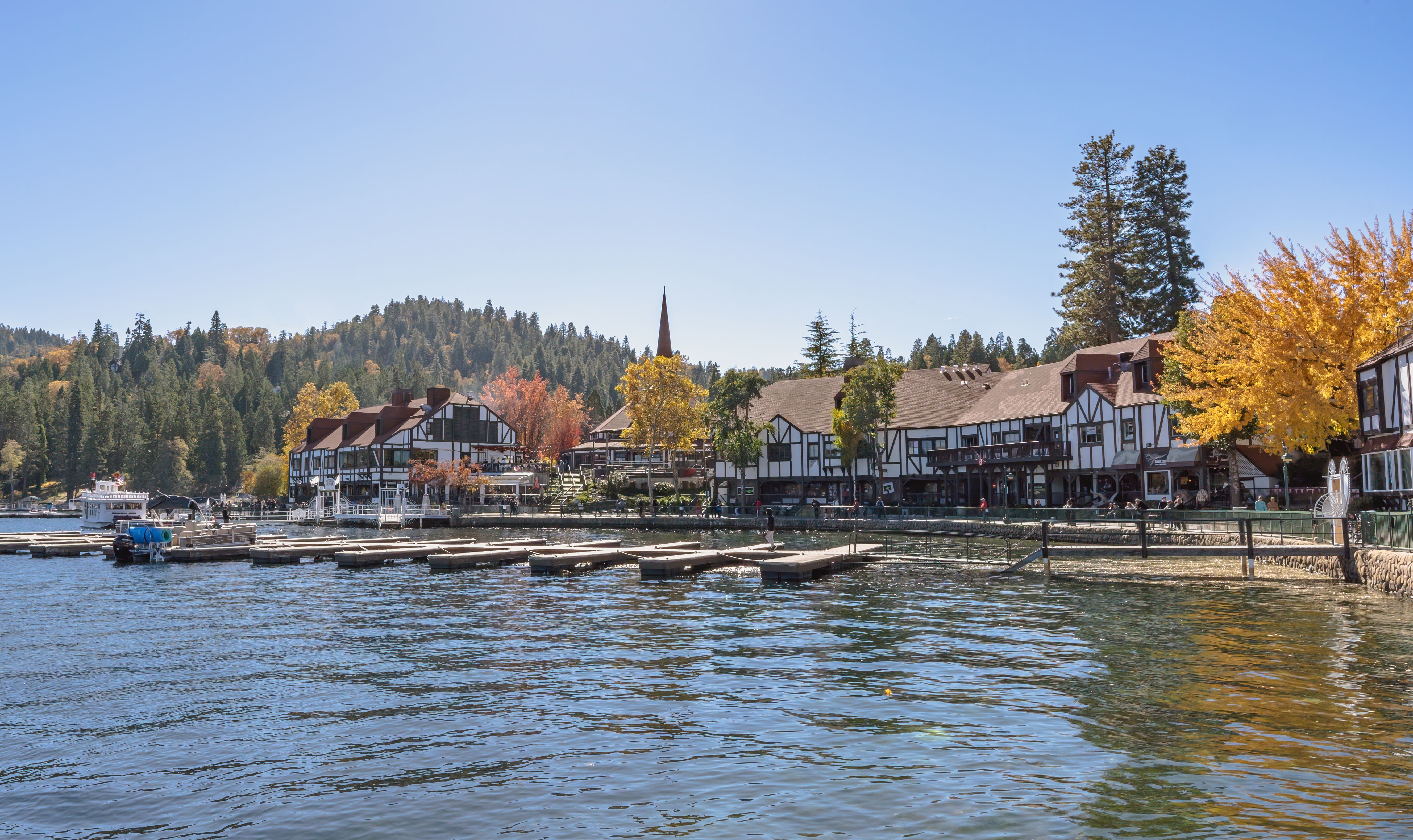 Charming Lake Arrowhead Village in fall with colorful trees and calm waters.