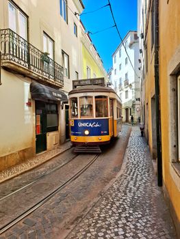Iconic Lisbon tram traversing narrow alleys in a picturesque scene of Portugal's capital.