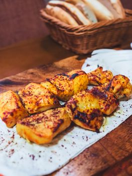Delicious grilled chicken skewers served on a wooden board with bread in the background.