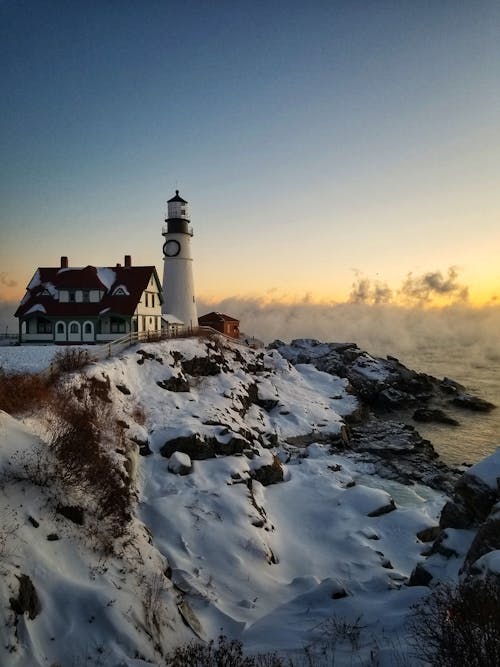 White and Black Lighthouse on Snow Covered Ground