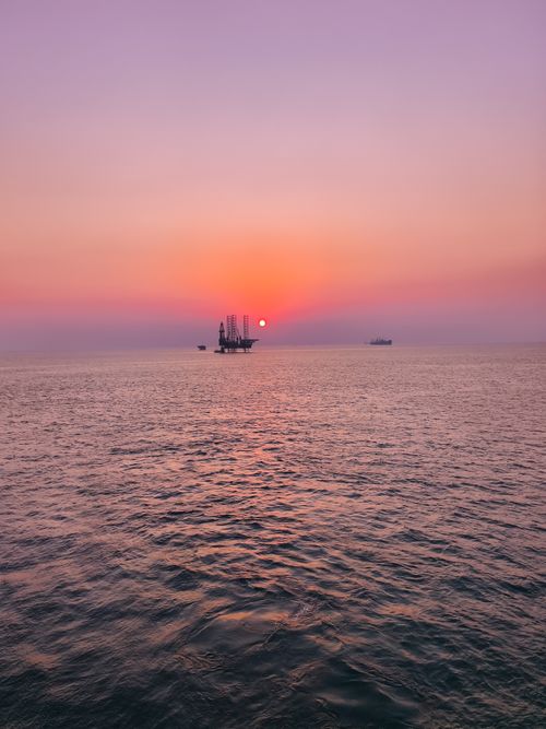 Free Tranquil sunset over the ocean with distant ships and a stunning pink sky. Stock Photo