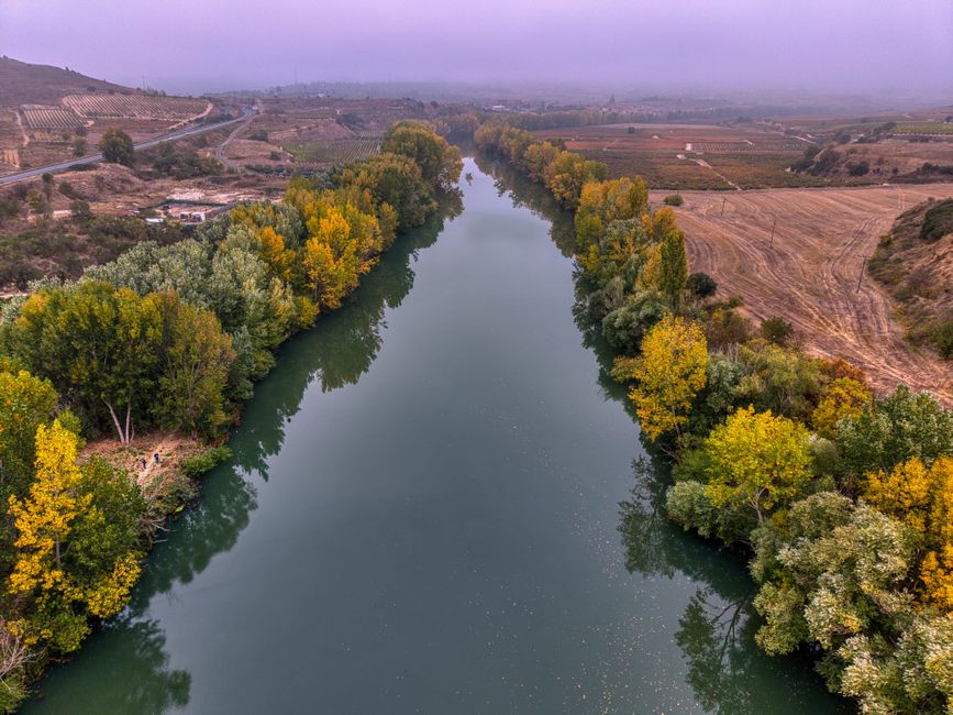 Aerial view of a serene river flowing through autumn foliage in La Rioja, Spain.