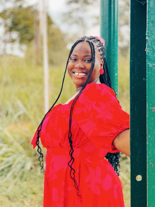Free A joyful woman in a vibrant red dress smiling outdoors, exuding positive vibes. Stock Photo
