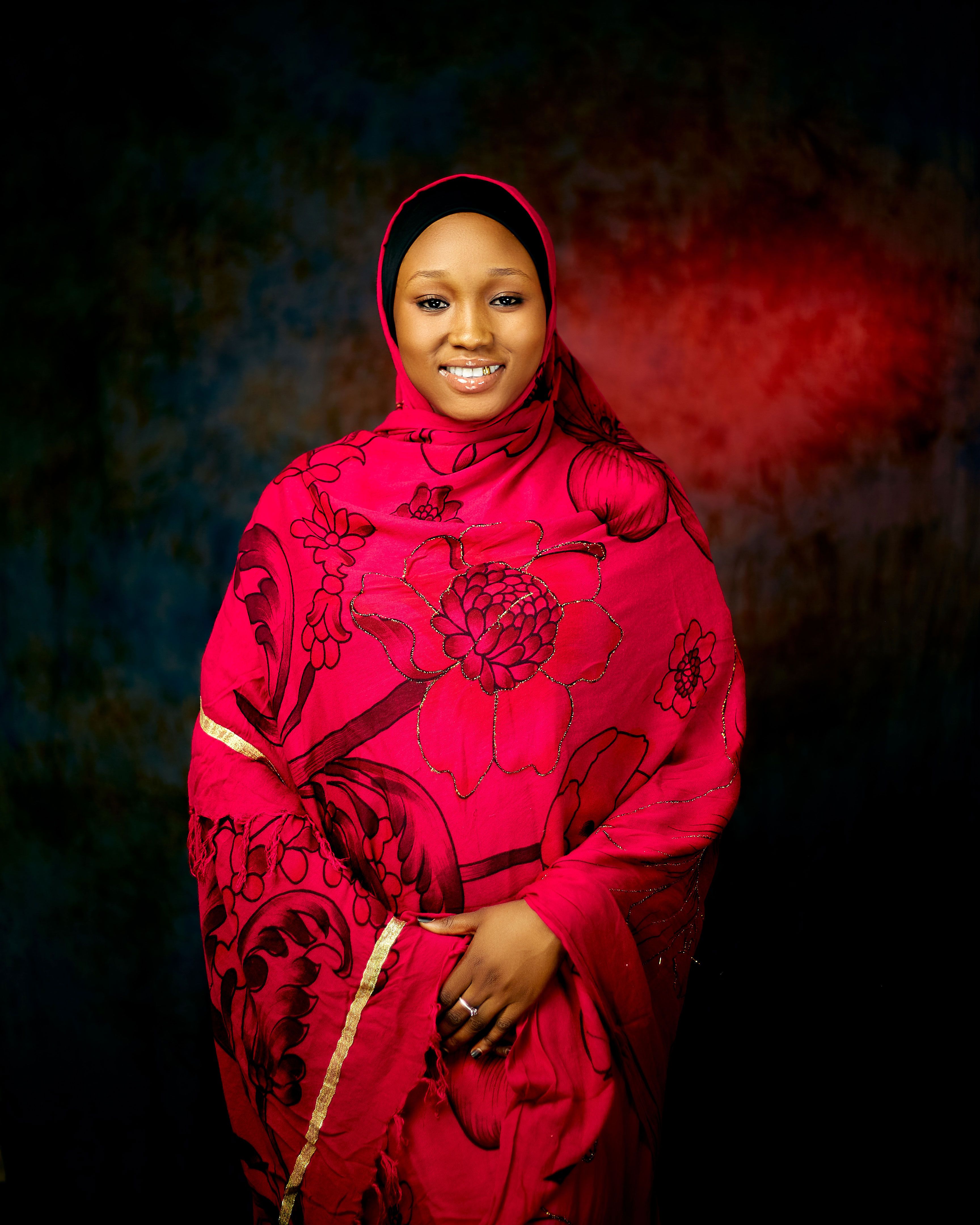 A woman wearing a vibrant red hijab with floral patterns, radiating elegance.