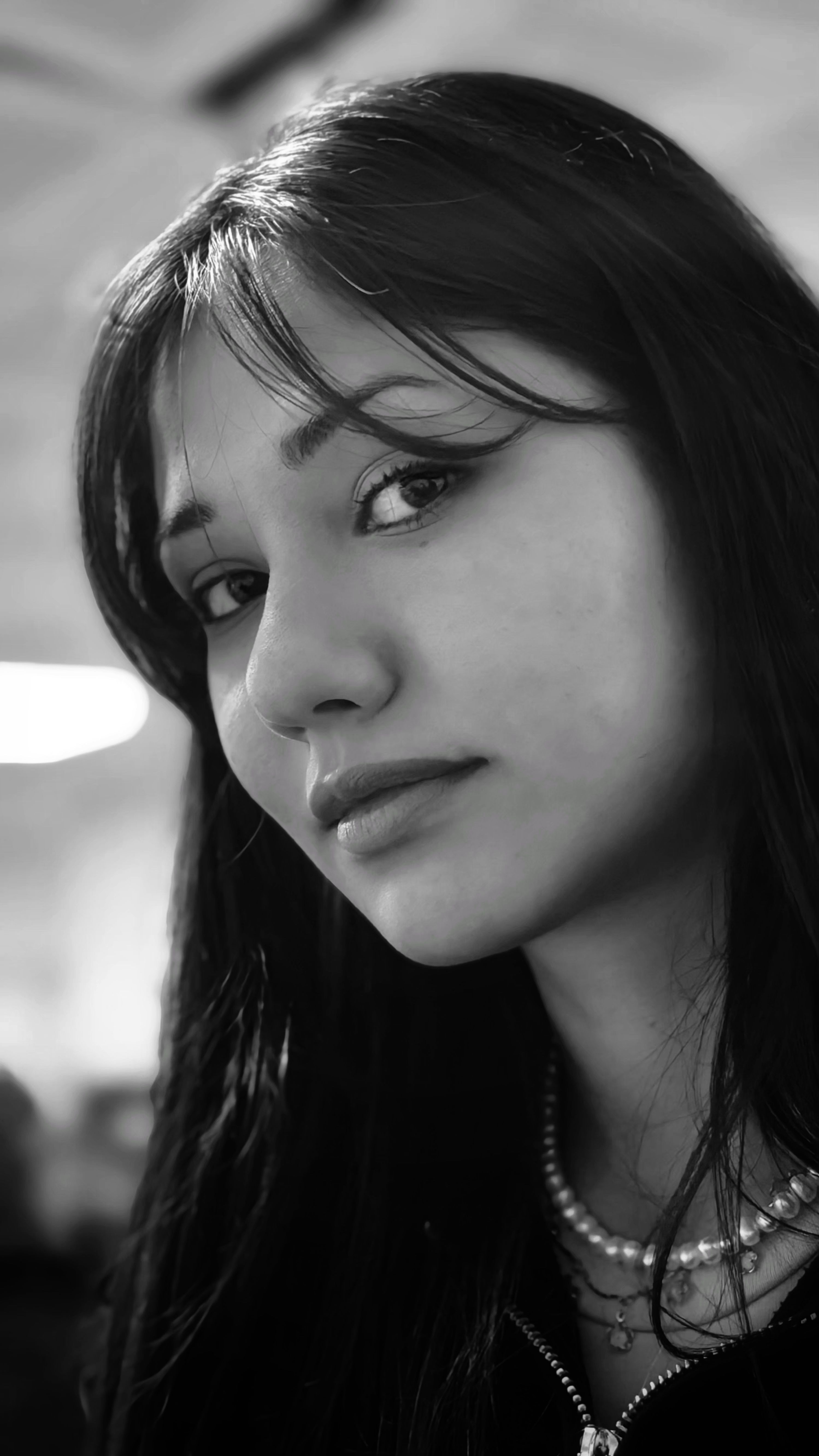 Striking black and white portrait of a young woman with long hair indoors.