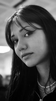 Striking black and white portrait of a young woman with long hair indoors.