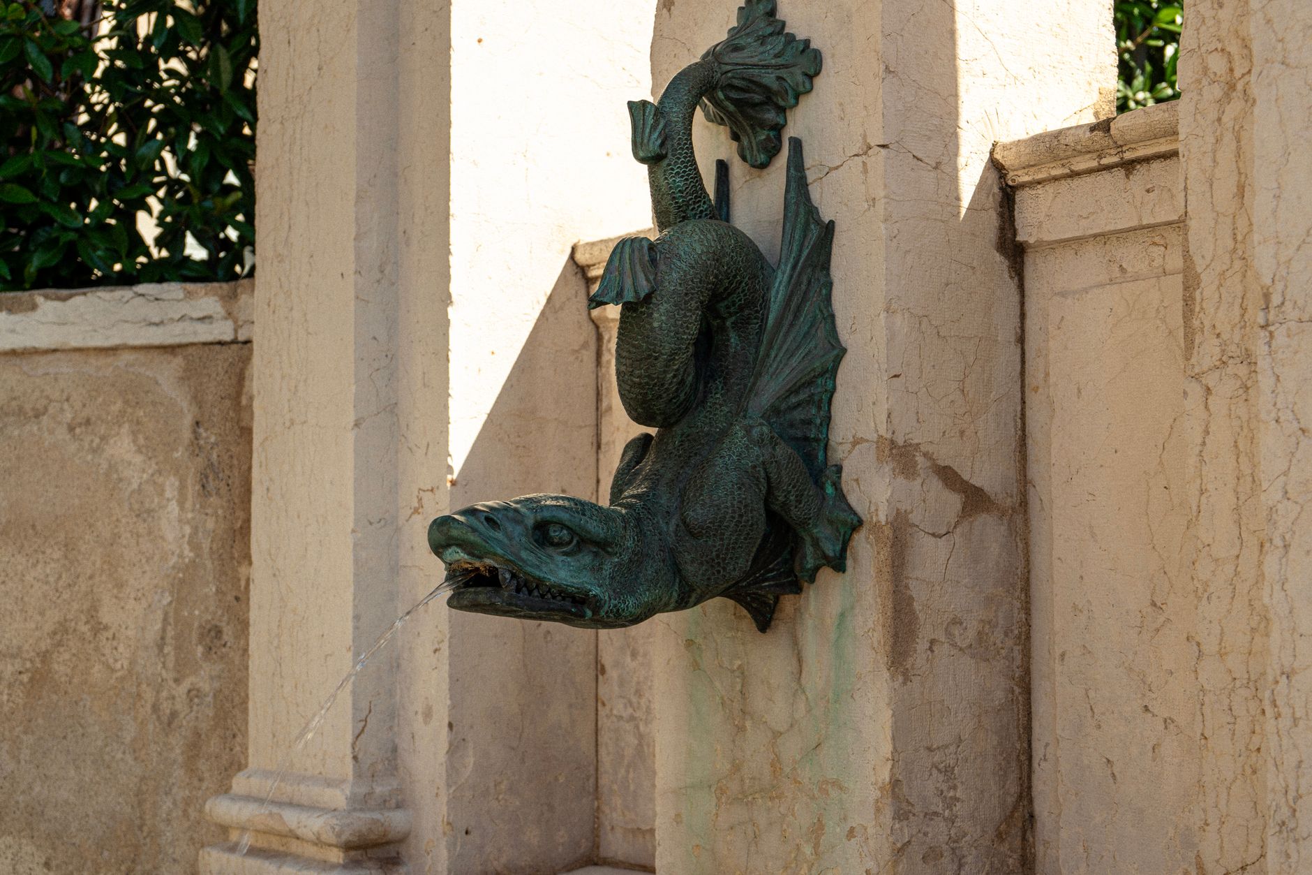 Intricate dragon fountain sculpture in historical Geneva architecture.