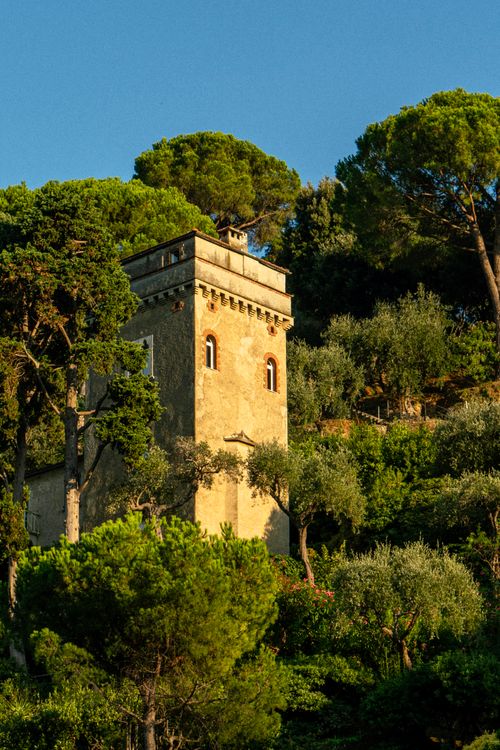Free A scenic view of a historical tower surrounded by lush greenery in Portofino, Italy. Stock Photo