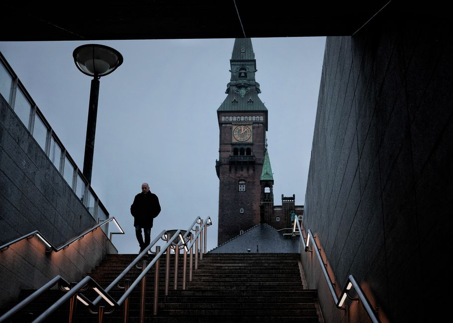 Dramatic urban scene featuring a person on stairs and historic tower in Copenhagen.