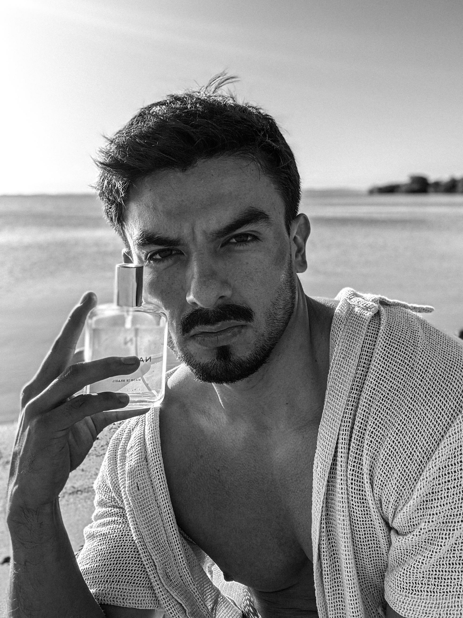 A male model poses with a perfume bottle by the beach in Porto Alegre, Brazil.