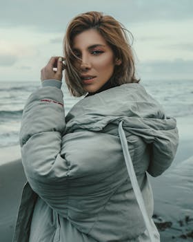 Portrait of a woman in a winter coat at the beach. Stylish and serene.