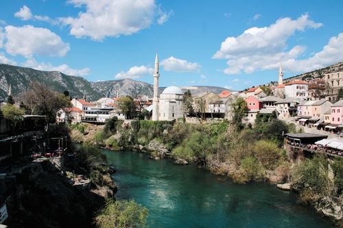 Free Picturesque view of Mostar's historic architecture with the Neretva River and a clear blue sky. Stock Photo
