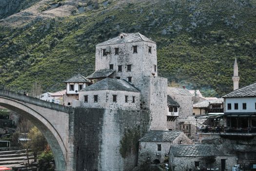 View of the iconic stone buildings and bridge in Mostar, Bosnia, highlighting its historic architecture and picturesque setting.
