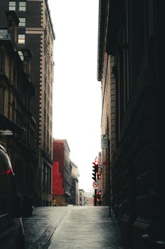 Street view of a narrow alley in Old Montreal with historic architecture and traffic lights.