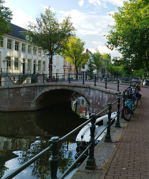 Free Picturesque Amsterdam canal with bikes and trees on a sunny day. Stock Photo