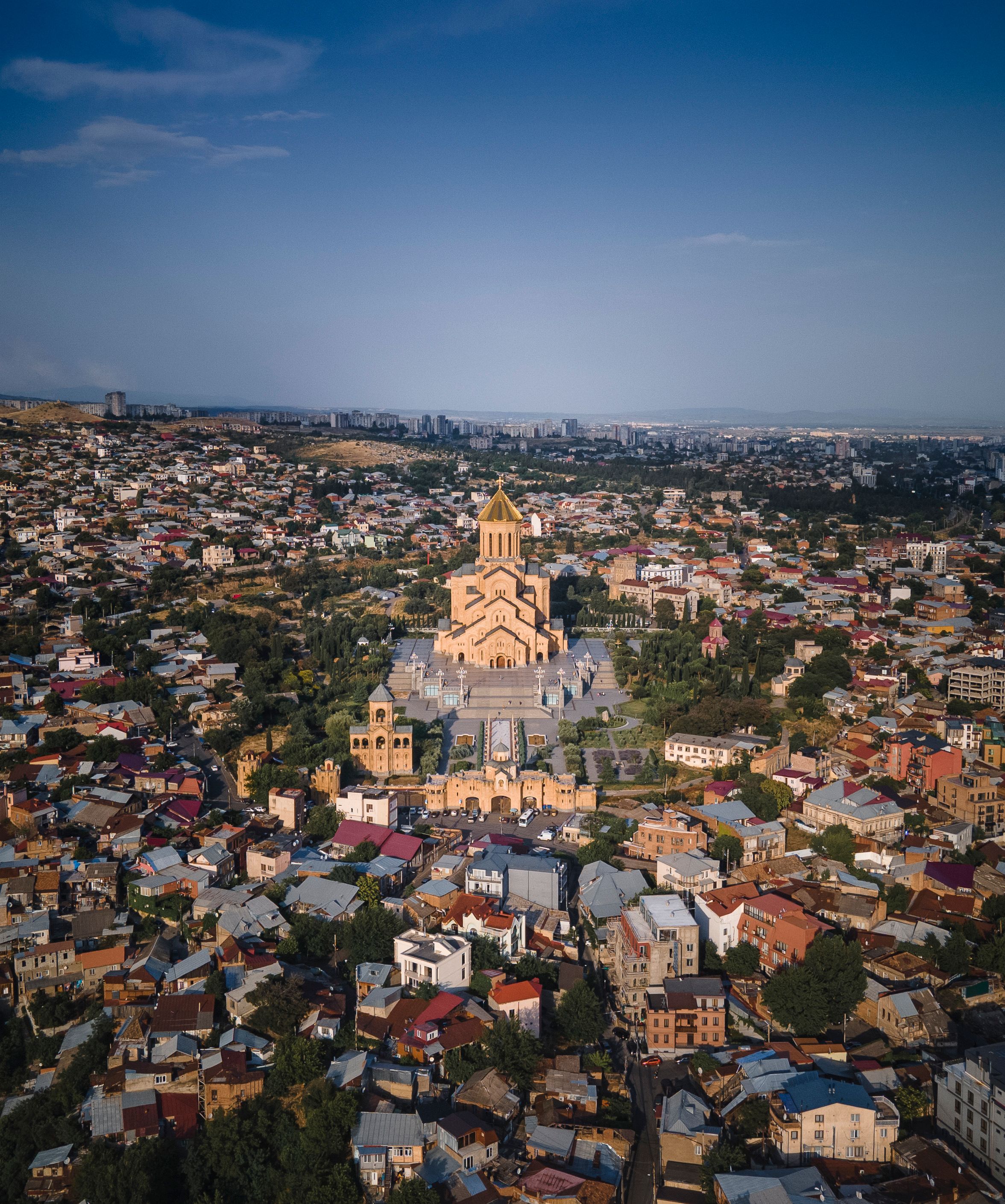 Stunning aerial view of the Holy Trinity Cathedral in Tbilisi, Georgia amidst urban landscape.