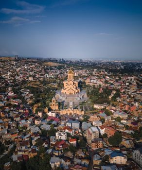 Stunning aerial view of the Holy Trinity Cathedral in Tbilisi, Georgia amidst urban landscape.