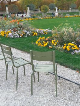 Serene autumn day in a Paris park with lush gardens and iconic green chairs.