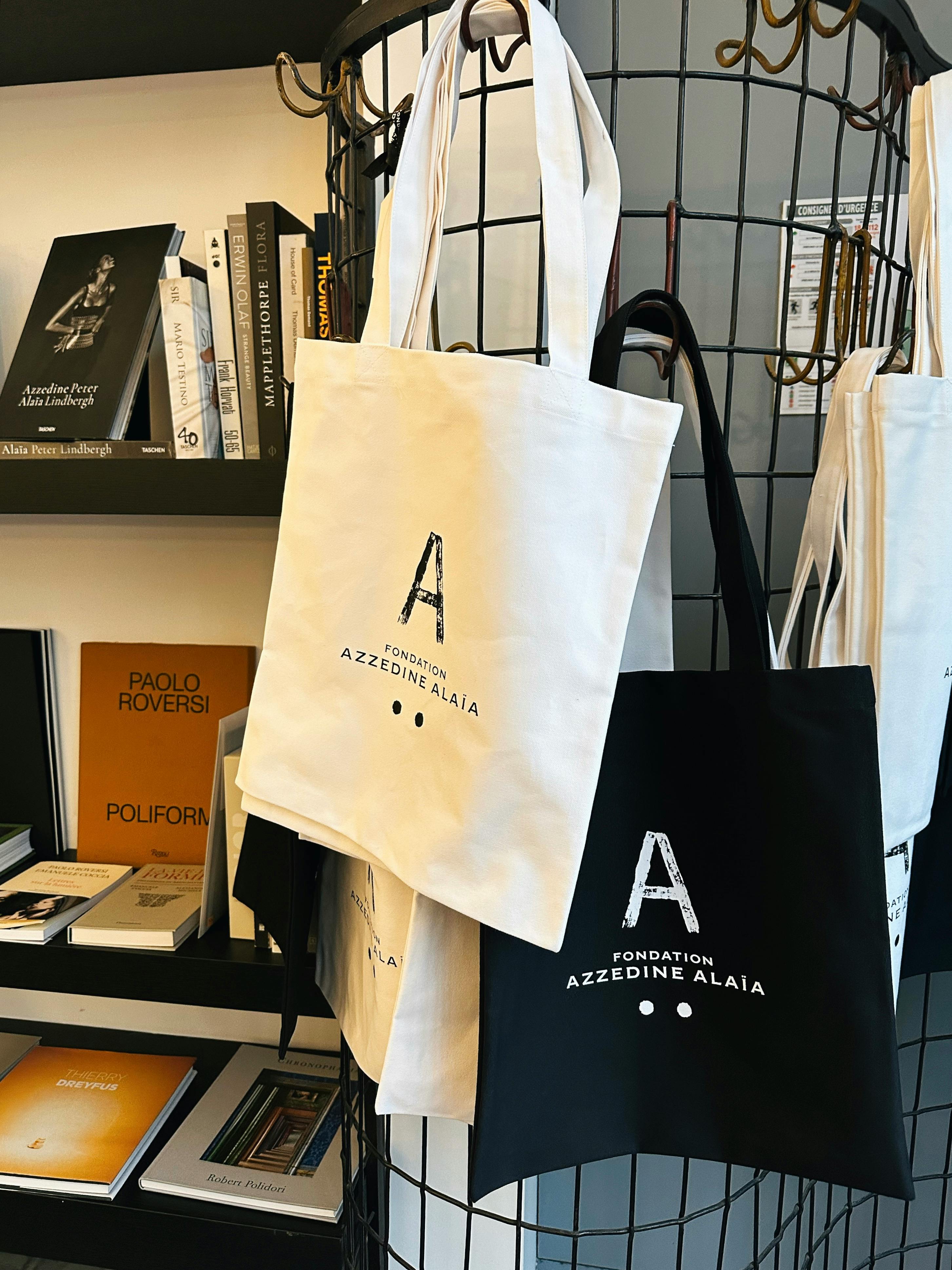 Elegant tote bags on display with books in a chic store setting.
