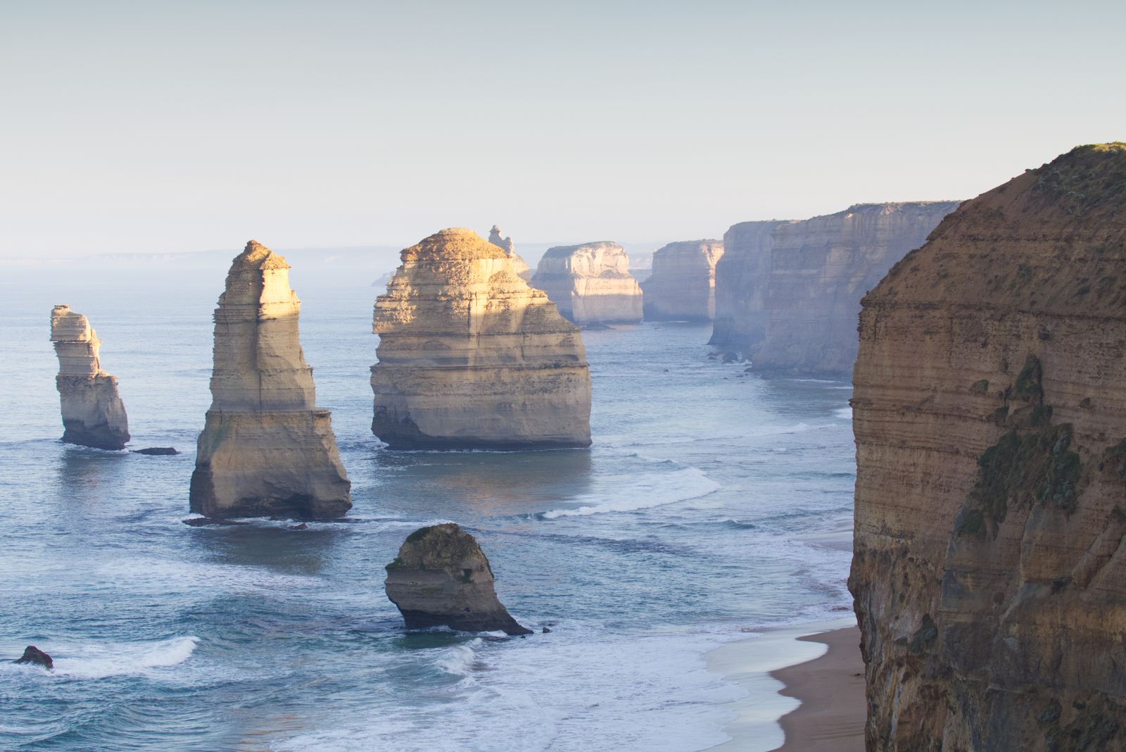 Limestone stacks of the Twelve Apostles rising from turquoise surf beside cliffs on the Great Ocean Road