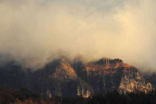 Serene autumn mountain landscape enveloped in mist under a soft, warm light at sunrise.
