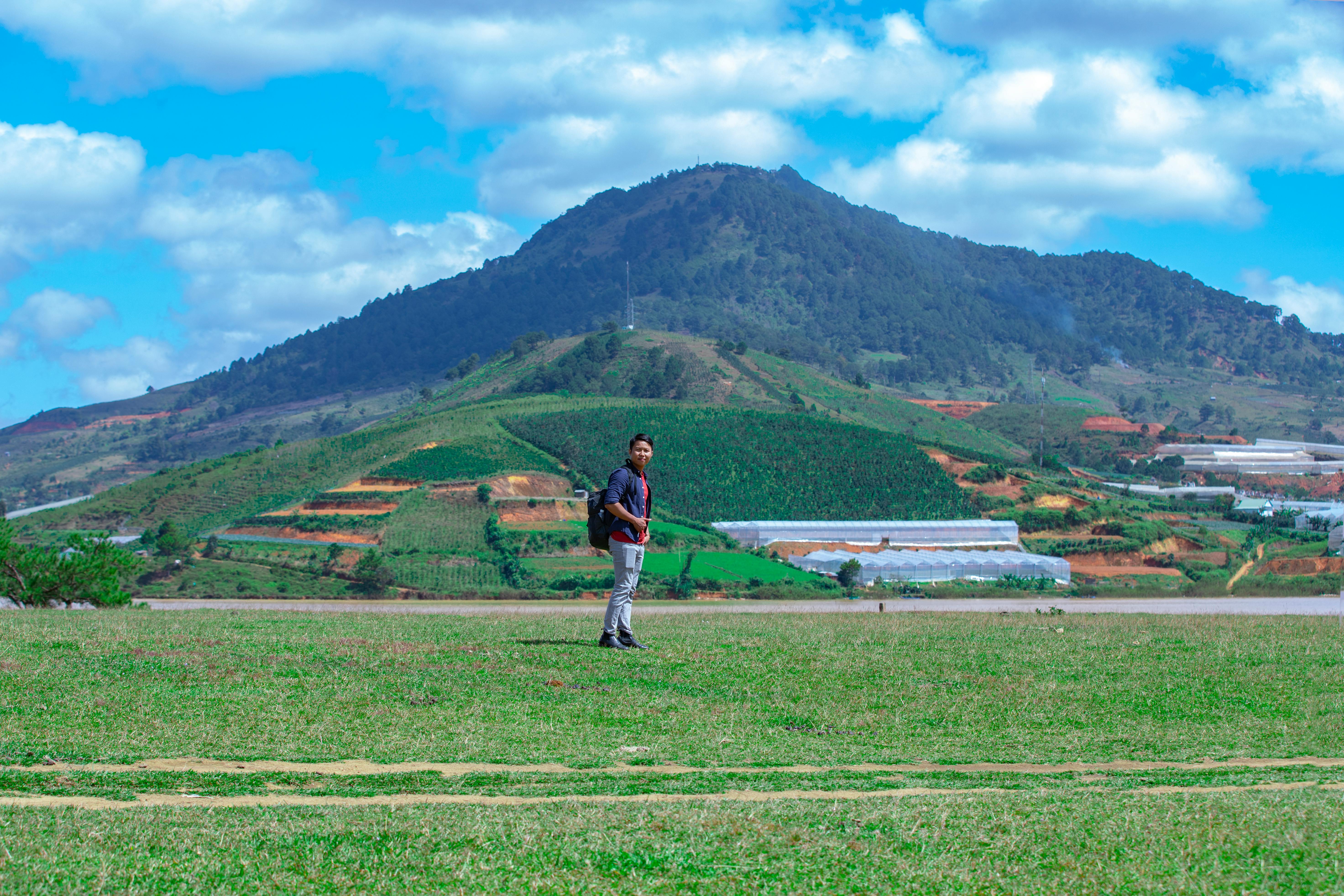 Jovem em campo verde com montanhas ao fundo, simbolizando a produtividade da pastagem.