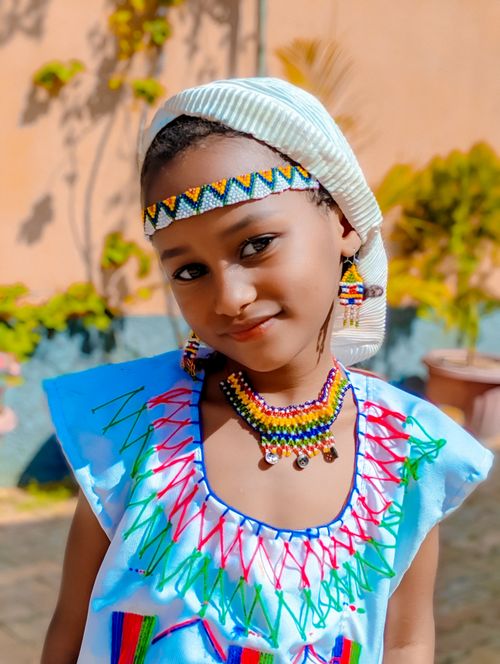 Free A young girl wearing vibrant traditional attire and bead accessories outdoors. Stock Photo