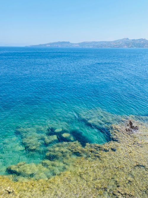 Free Breathtaking view of the clear blue waters along the rocky Aegean coastline under a bright summer sky. Stock Photo