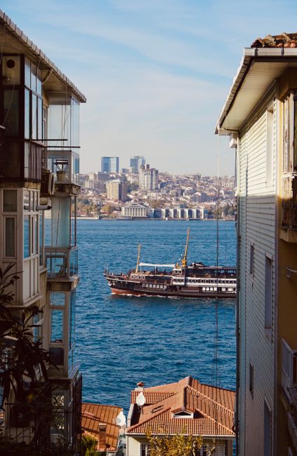 Ship sailing on Bosphorus Strait framed by buildings in Istanbul, under a clear sky.