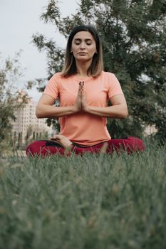 Serene outdoor meditation of an adult woman practicing yoga in a city park.