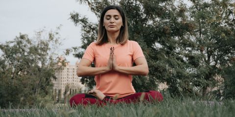 Woman practicing yoga and meditation in park. Enhancing mindfulness and relaxation outdoors.