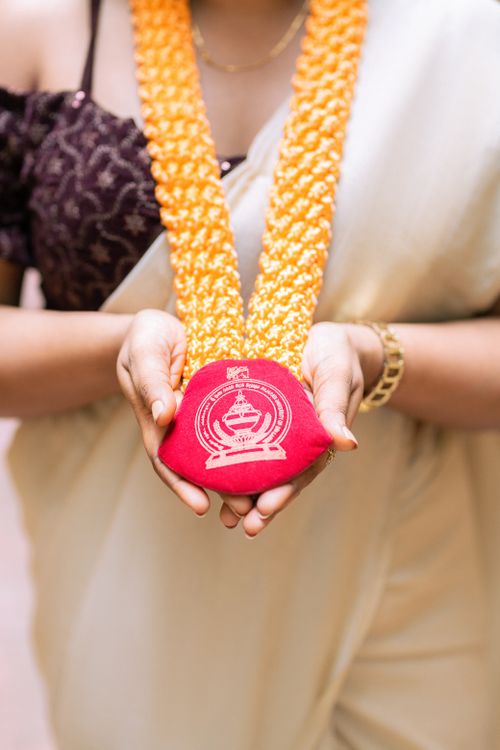 Free Close-up of hands holding a graduation medallion with a garland, symbolizing achievement and cultural traditions in Sri Lanka. Stock Photo