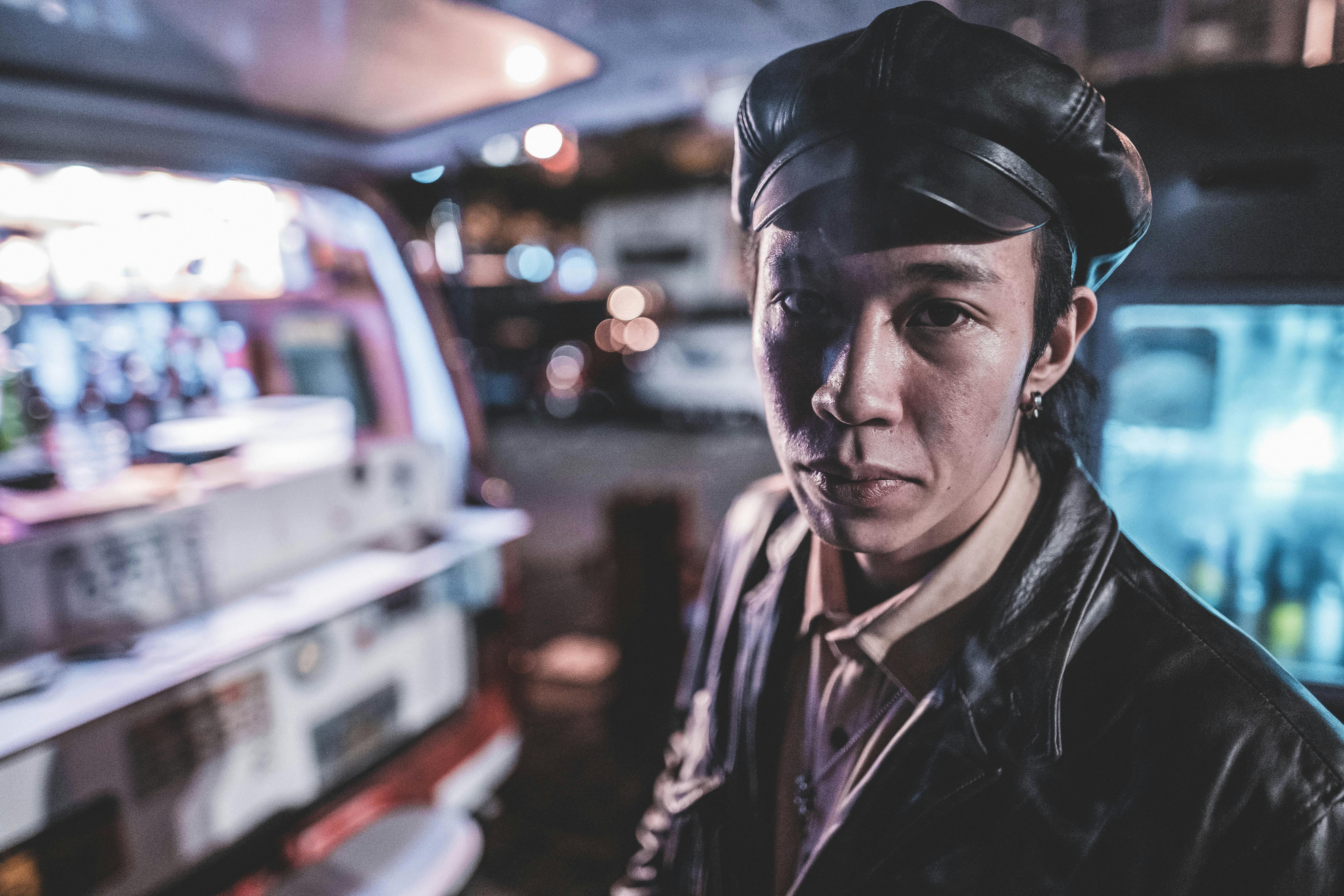 在充满活力的夜市里，时尚的人穿着黑色皮夹克，戴着帽子