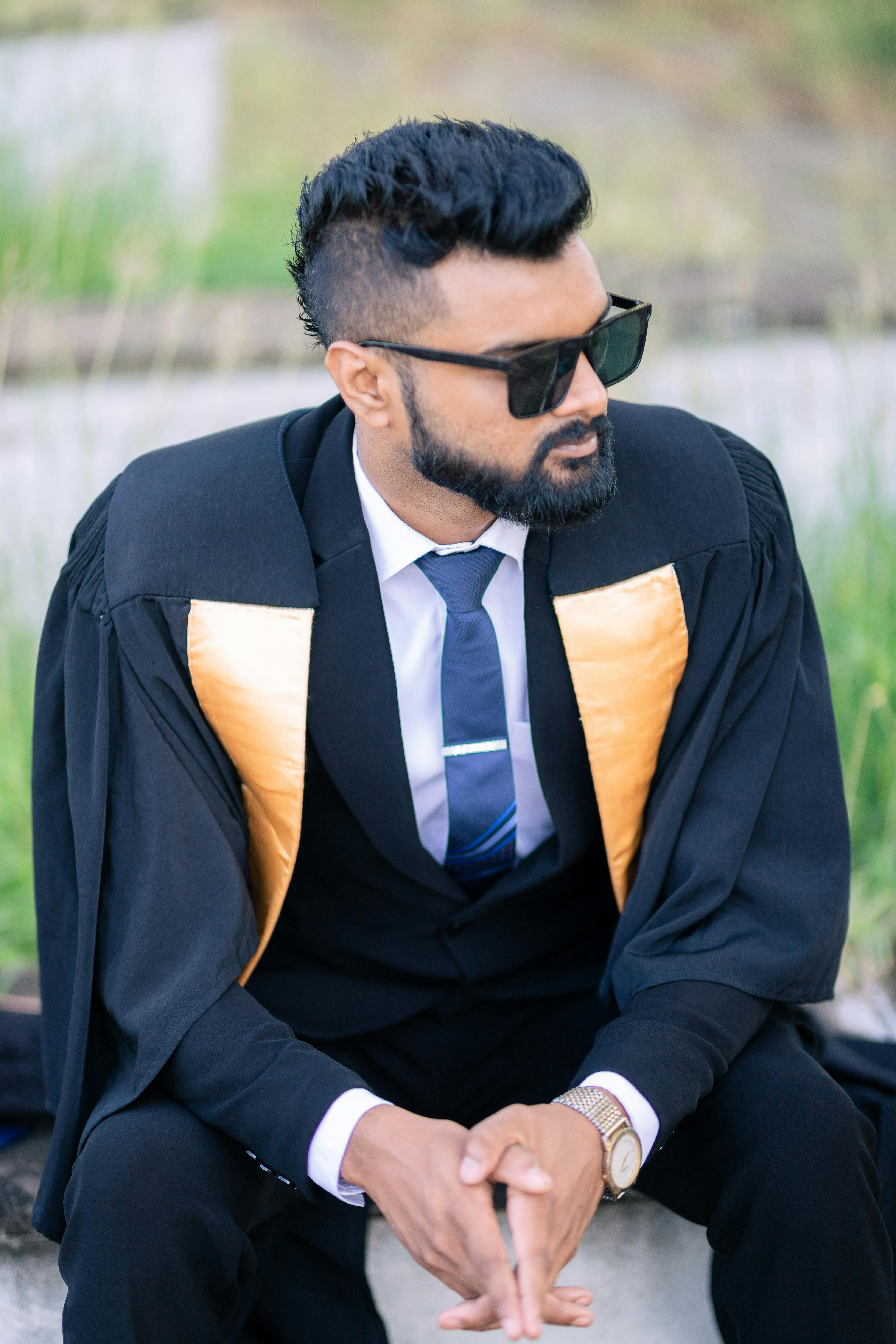 A stylish graduate in academic attire sitting confidently outdoors in Sri Lanka.