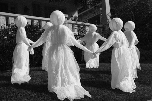 Free Eerie ghostly figures in white cloth arranged in a circle, creating a haunting scene. Stock Photo