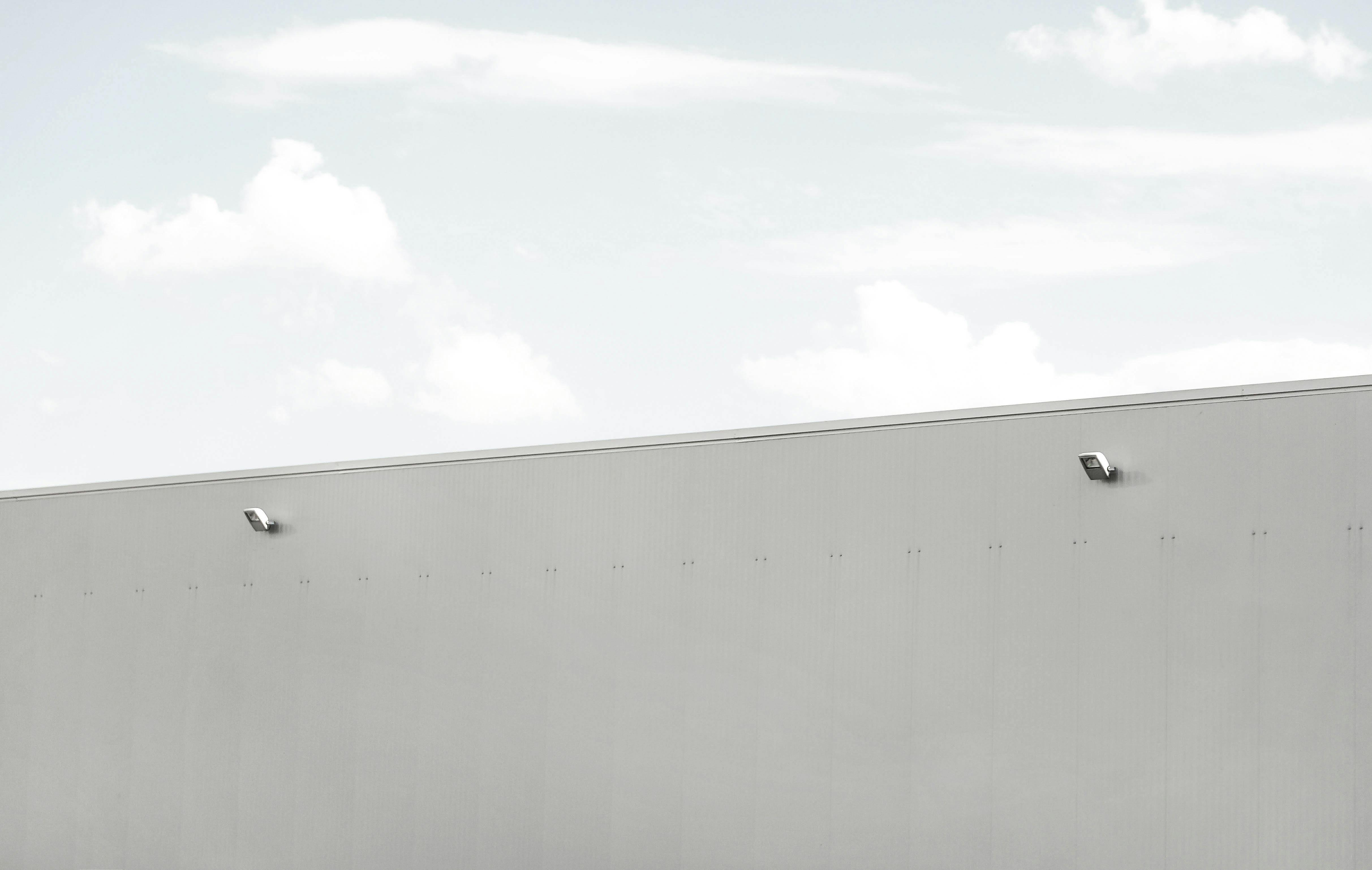 Gratis En minimalistisk industribygningsfacade med en klar blå himmel som baggrund, der understreger enkelhed og moderne design. Lagerfoto