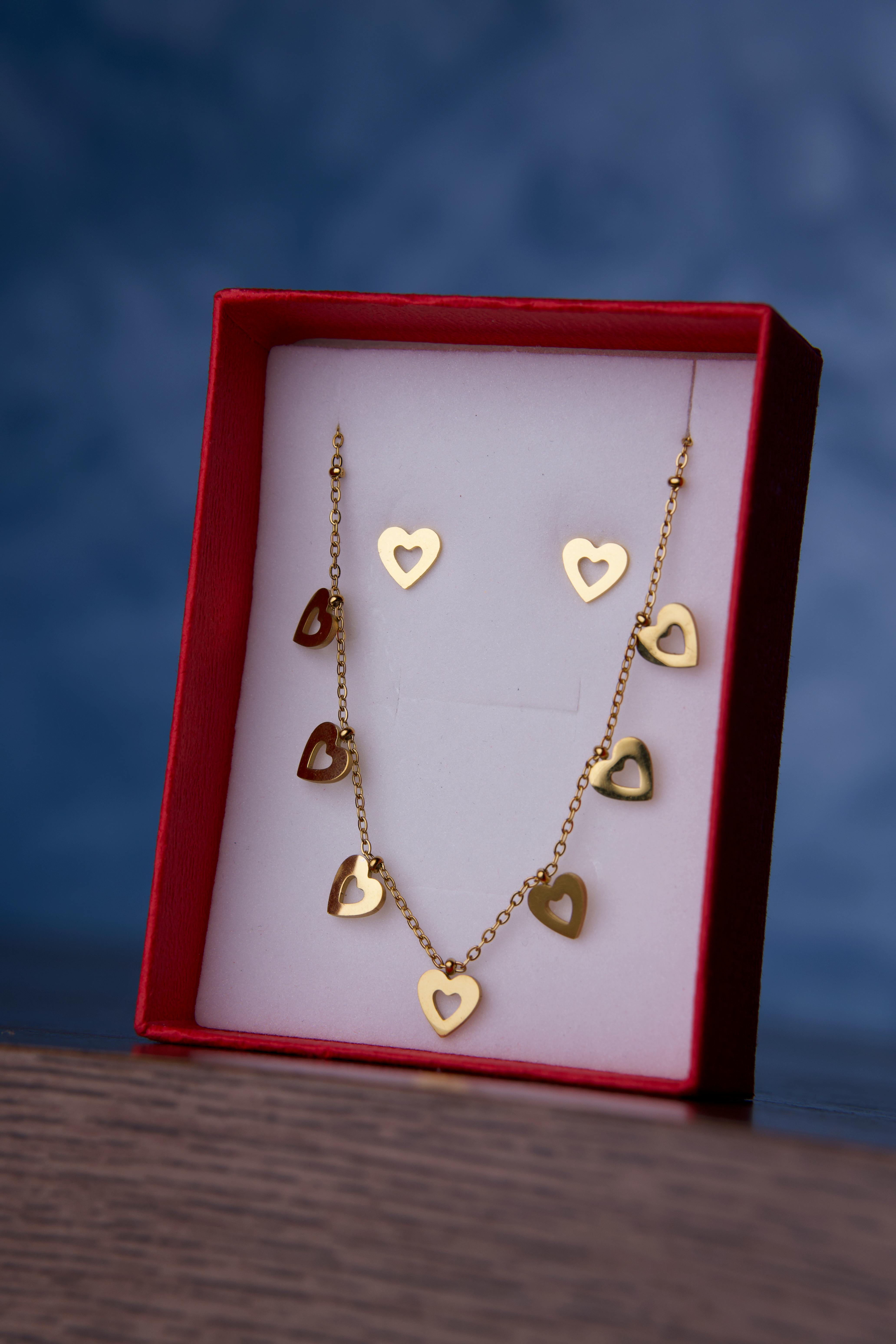 Elegant gold heart necklace and earrings set displayed in a red box, perfect gift for special occasions.