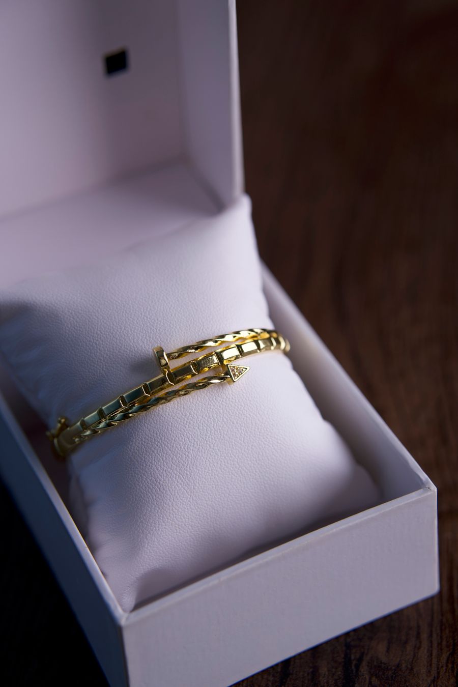 Gold bracelet in an open gift box on a wooden surface