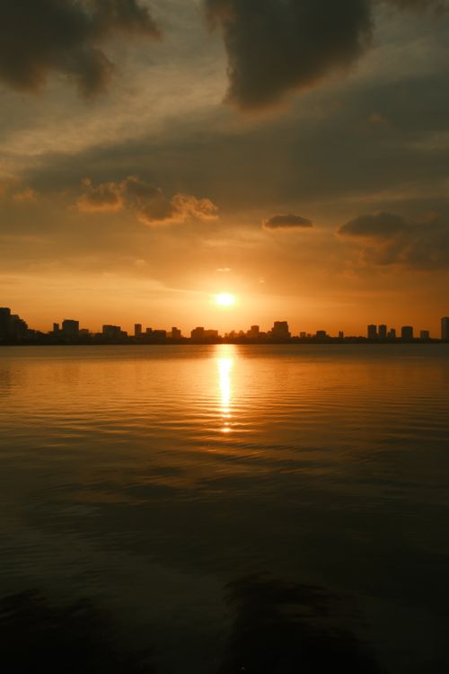 Free Stunning sunset over a California city skyline with beautiful reflections on the water, creating a warm and serene atmosphere. Stock Photo