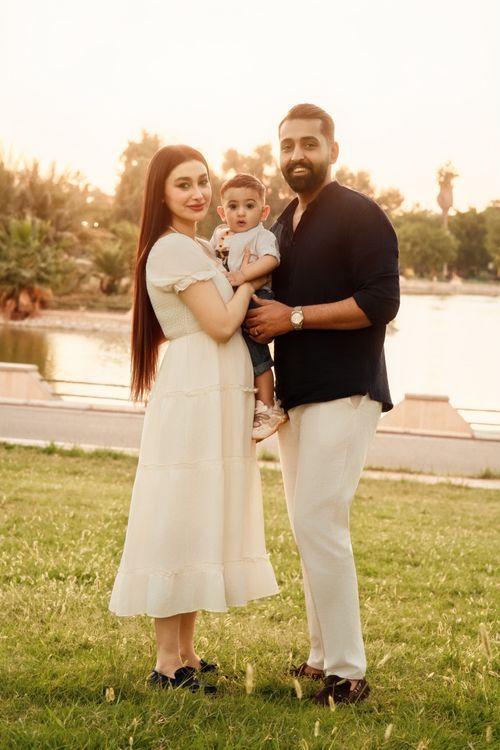 Free A family of three enjoying a serene sunset in a park. Stock Photo