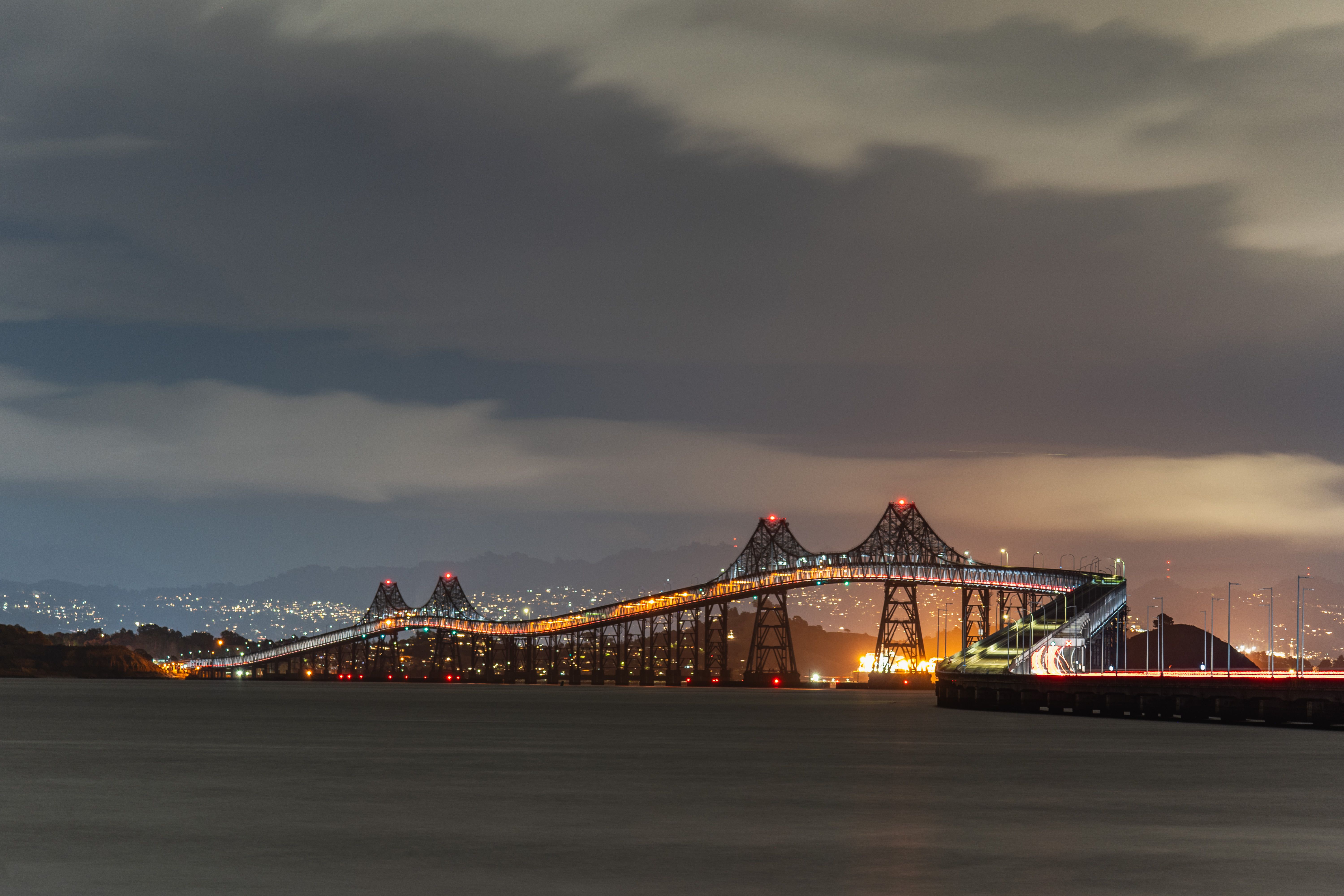 A stunning night view of the Richmond-San Rafael Bridge with city lights and cloudy sky.