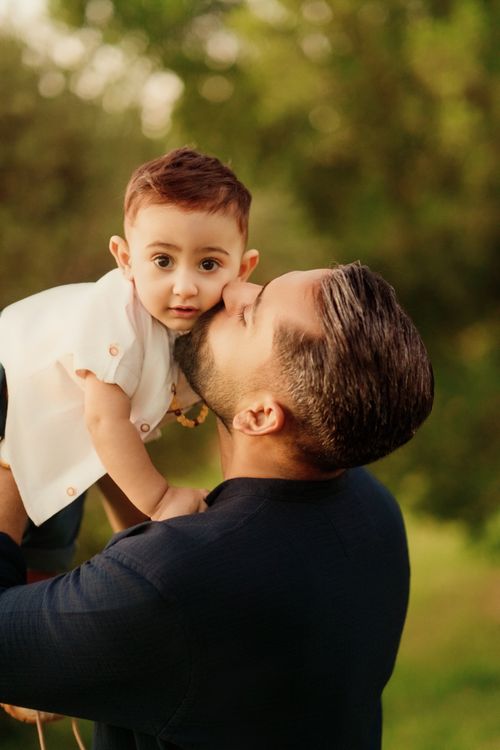 Free A sweet moment of a father kissing his baby child outdoors, showcasing love and family connection. Stock Photo
