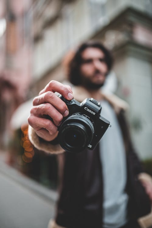 Shallow Photo of Person Holding Black Canon Dslr Camera