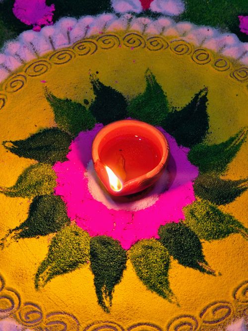 Free Vibrant Rangoli design with a lit diya at its center, symbolizing Diwali festivities. Stock Photo