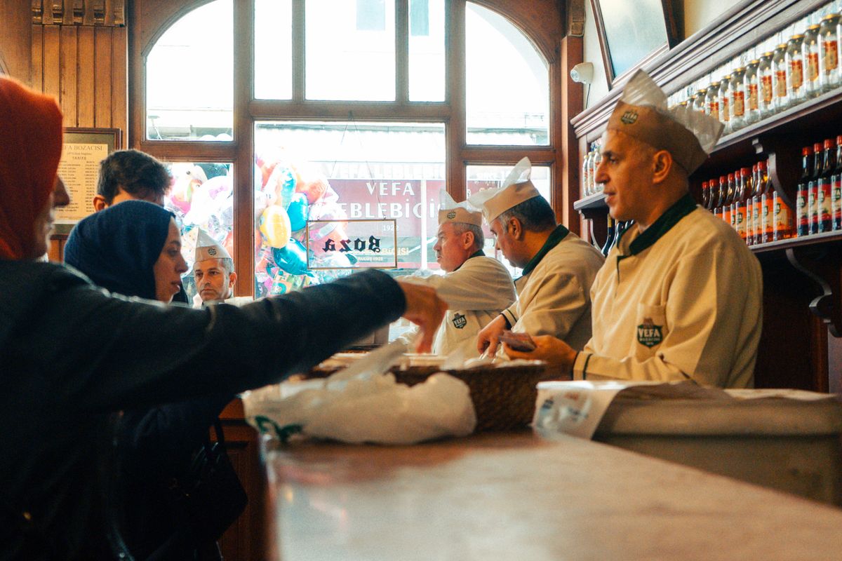 People interacting in a classic Turkish sweet shop with chefs serving.