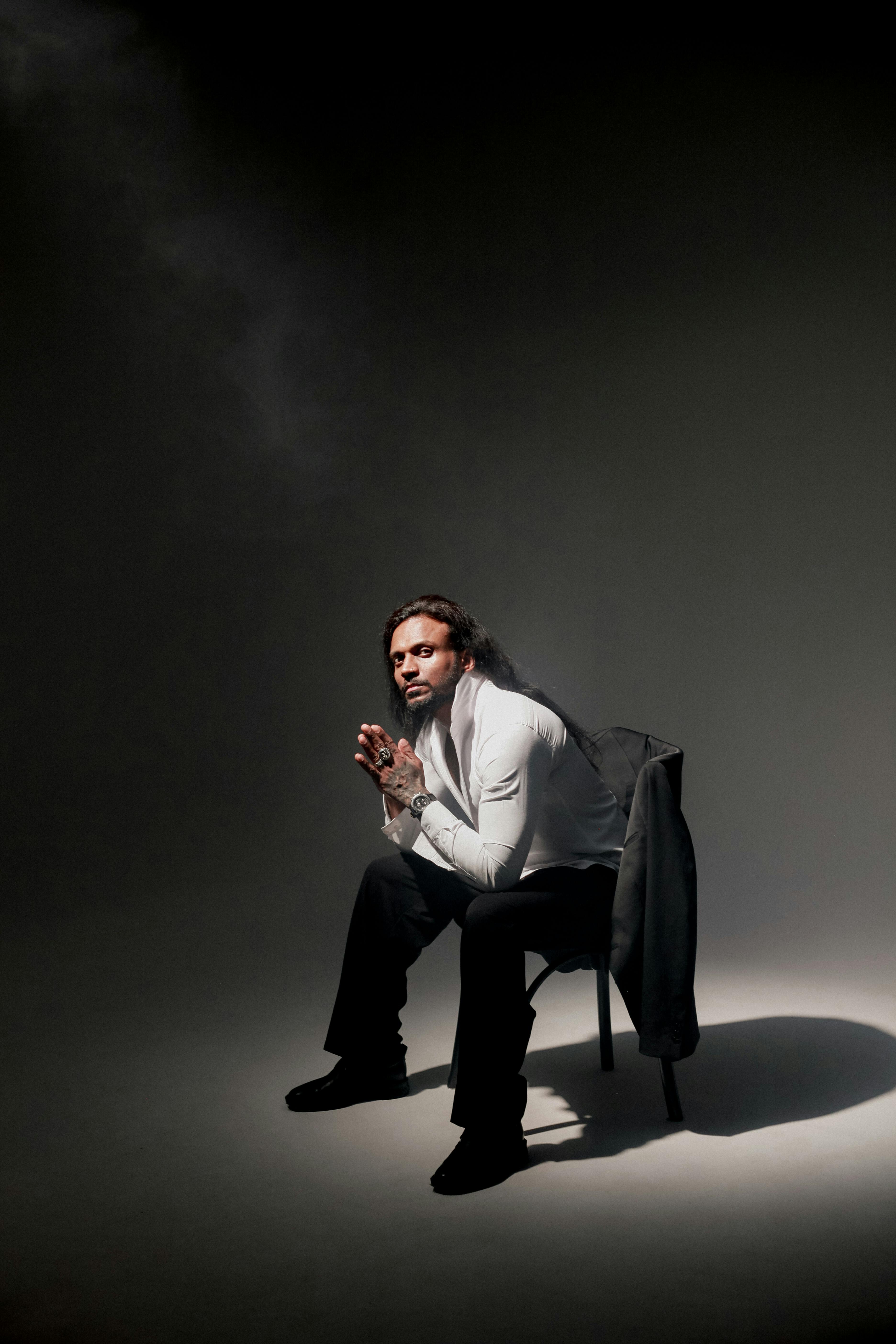 Stylish portrait of a man in dark studio setting, exuding mystery and elegance.