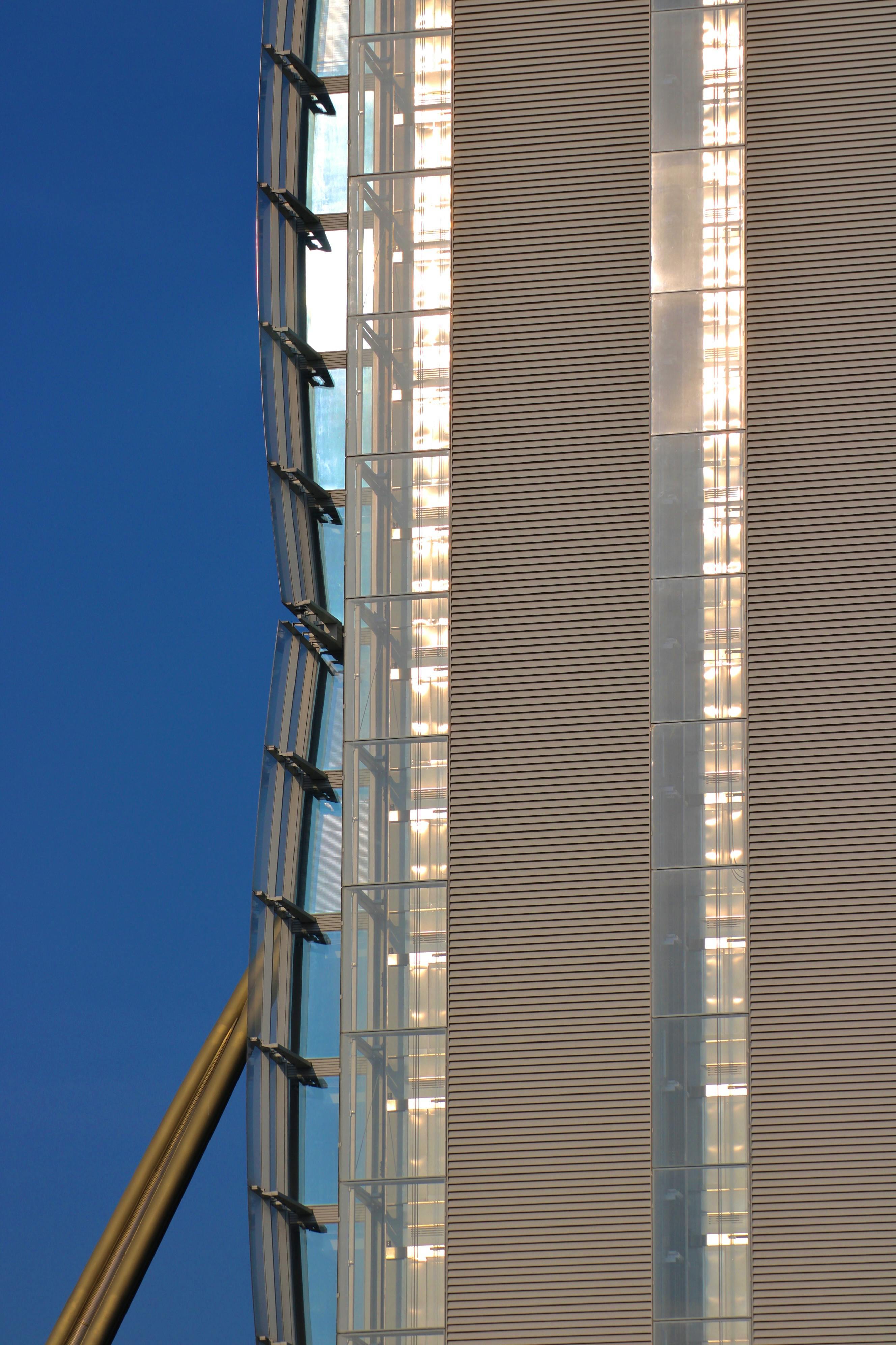 Gratis Nærbillede af en moderne skyskraberfacade med glas- og metalelementer mod en blå himmel. Lagerfoto