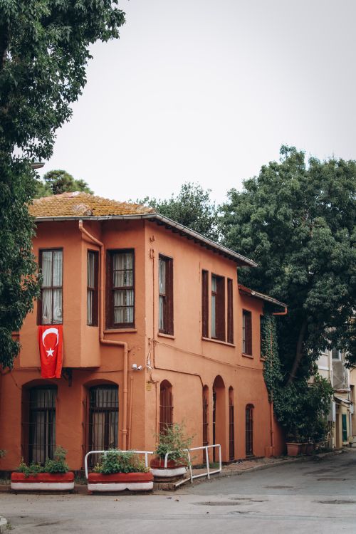 Free Historic orange building adorned with Turkish flag, surrounded by lush trees. Stock Photo