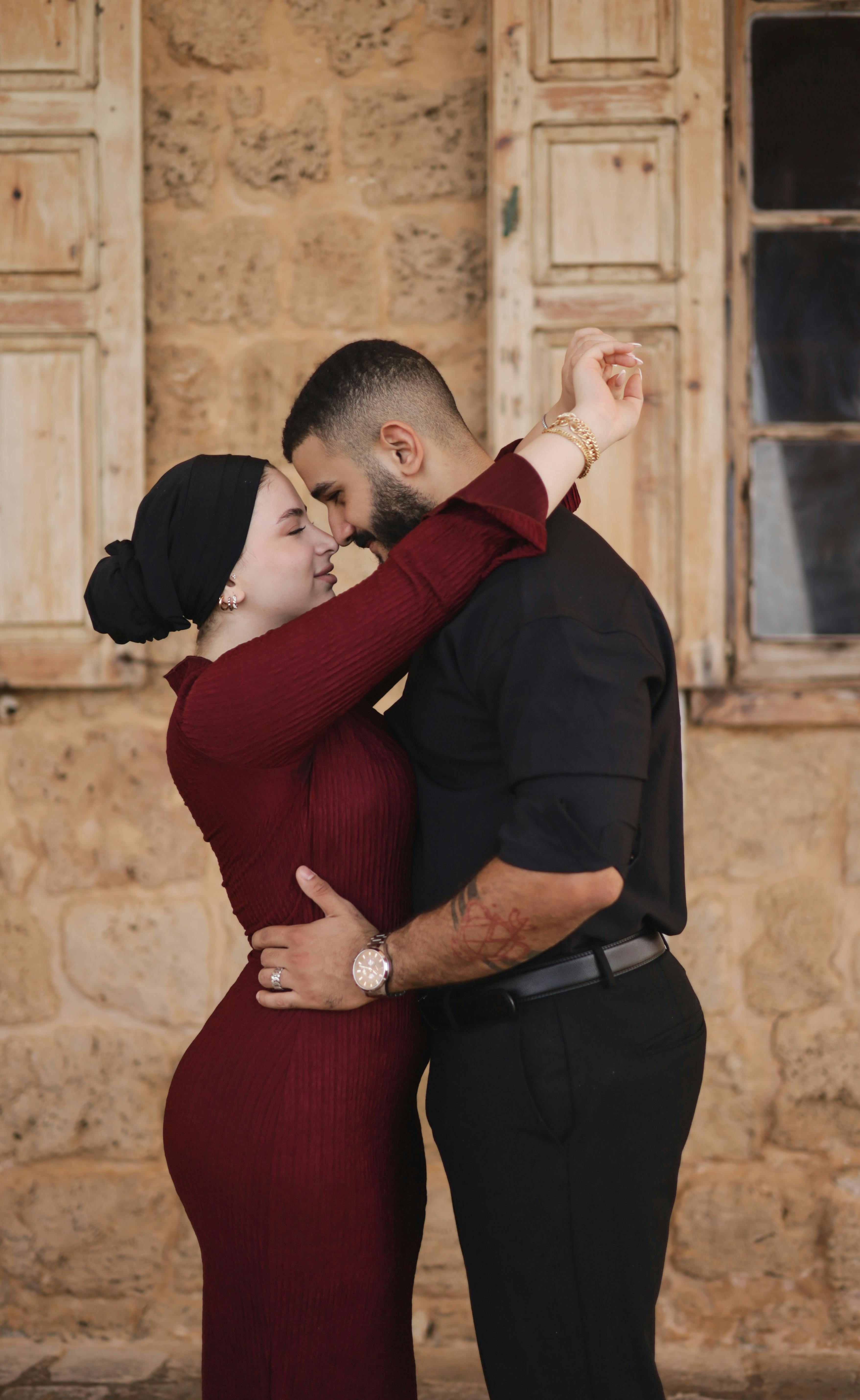 Couple embracing with love in front of a rustic stone backdrop, exuding warmth and intimacy.